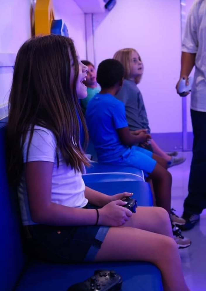 Girl laughing with controller inside mobile gaming trailer