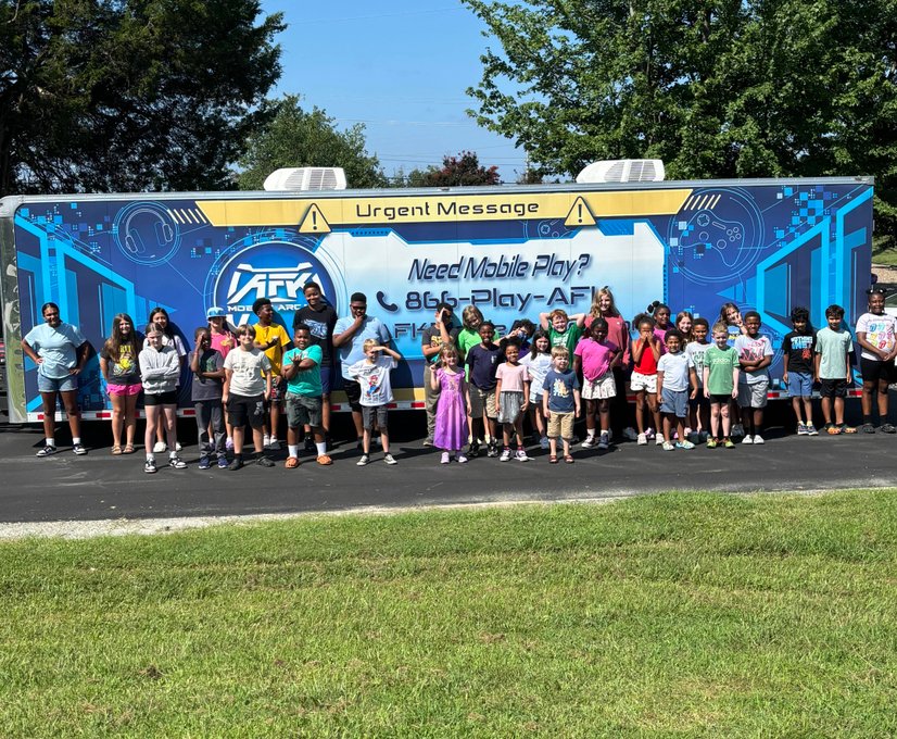 Large group of children posing before gaming trailer